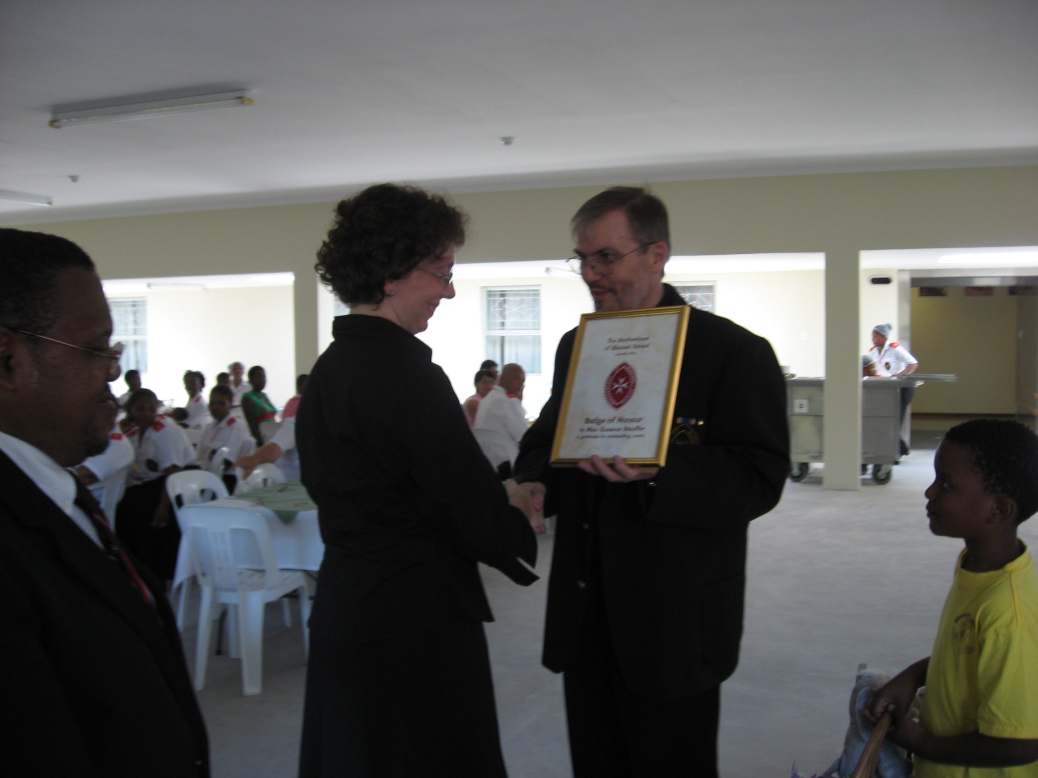 Father Gérard presenting the Badge of Honour certificate to Susanne Stauffer